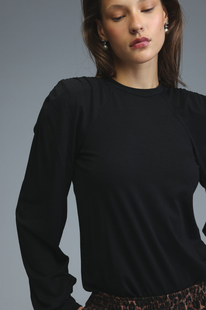 Black long-sleeved padded shirt with ruched shoulders and soft flowing fabric shown from the front