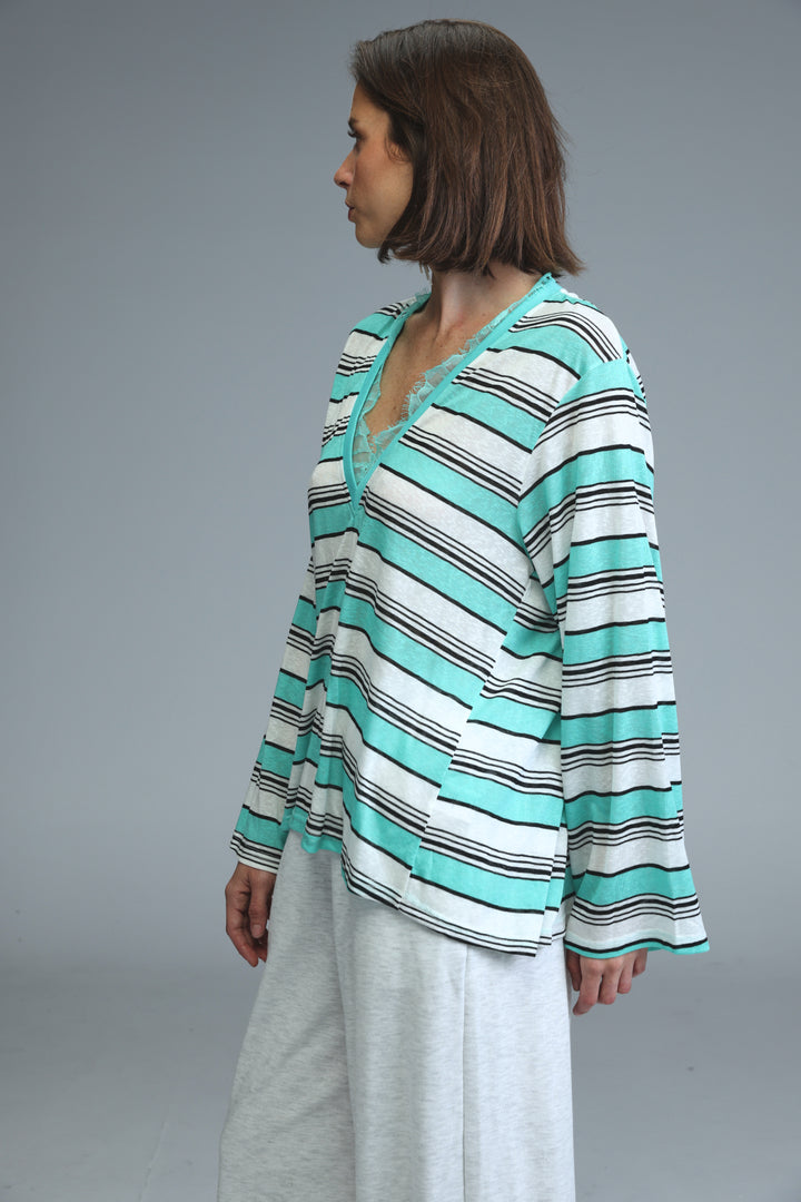 A woman wearing a front view of a glow mint striped shirt with teal, white, and black horizontal stripes and v-neckline