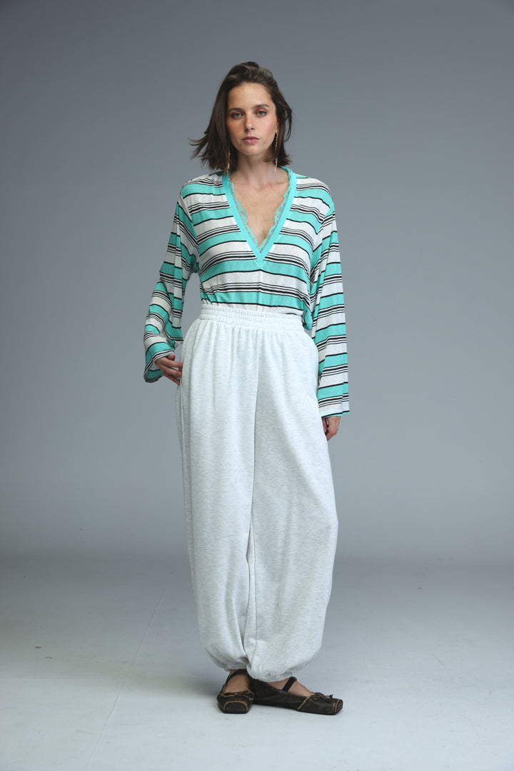 A woman wearing a teal and white striped glow mint long-sleeved v-neck shirt shown from the front