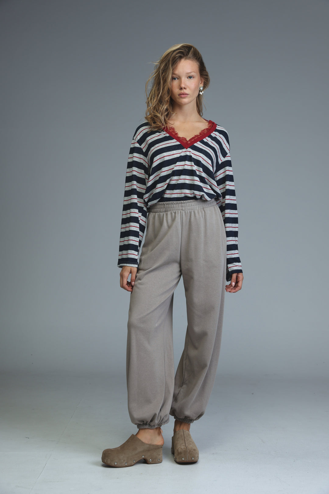 A woman wears a glow blue striped long-sleeved top with red lace trim at the neckline front view