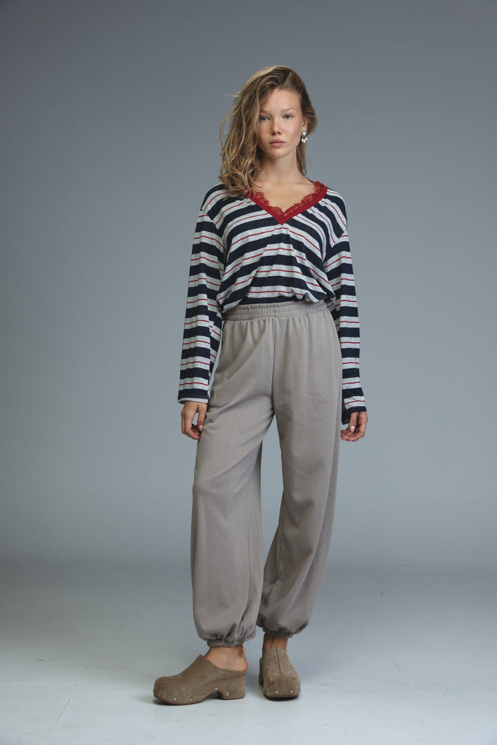 A woman wears a glow blue striped long-sleeved top with red lace trim at the neckline front view