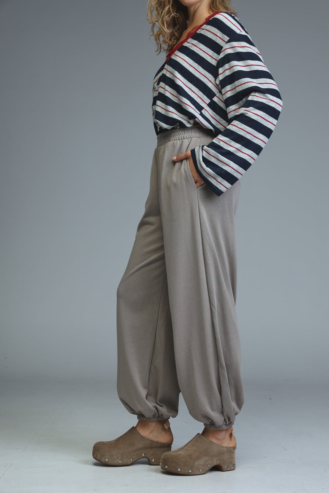 Beige joggers with a loose fit and elastic cuffs shown from the front paired with a striped top and wooden sole shoes