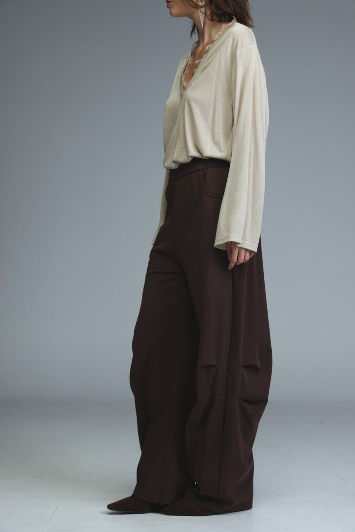 Brown joggers paired with a cream-colored loose-fitting long-sleeve blouse with v-neckline and ruching at cuffs