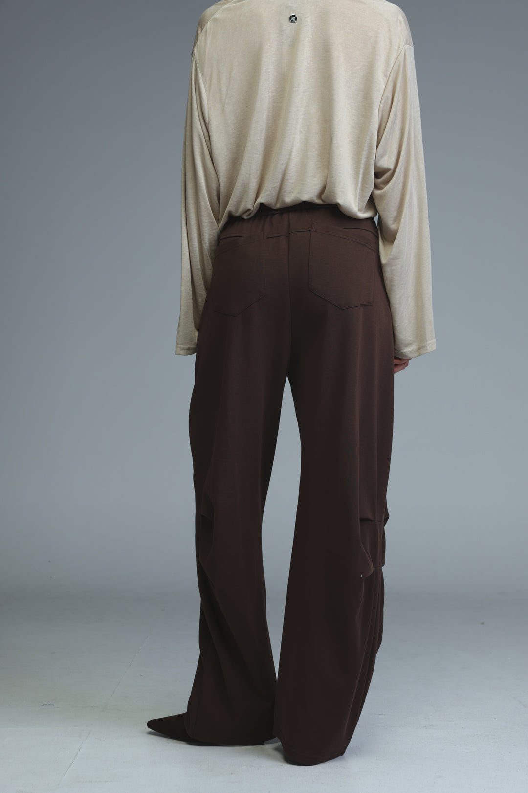 The back view of beige long-sleeved top paired with 646 brown joggers wide-leg trousers