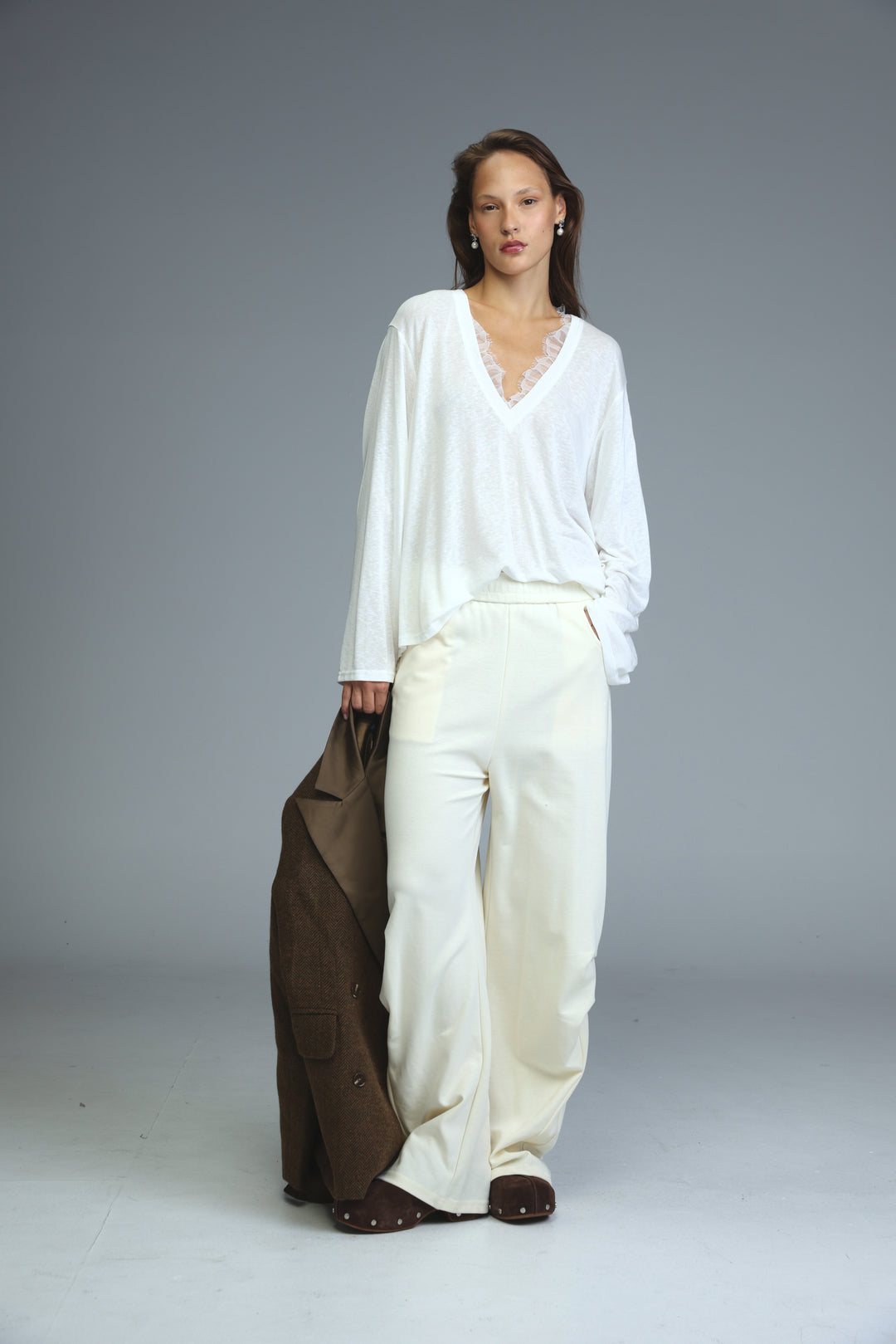 Cream joggers paired with a flowing white blouse featuring delicate lace trim at the v-neckline front view