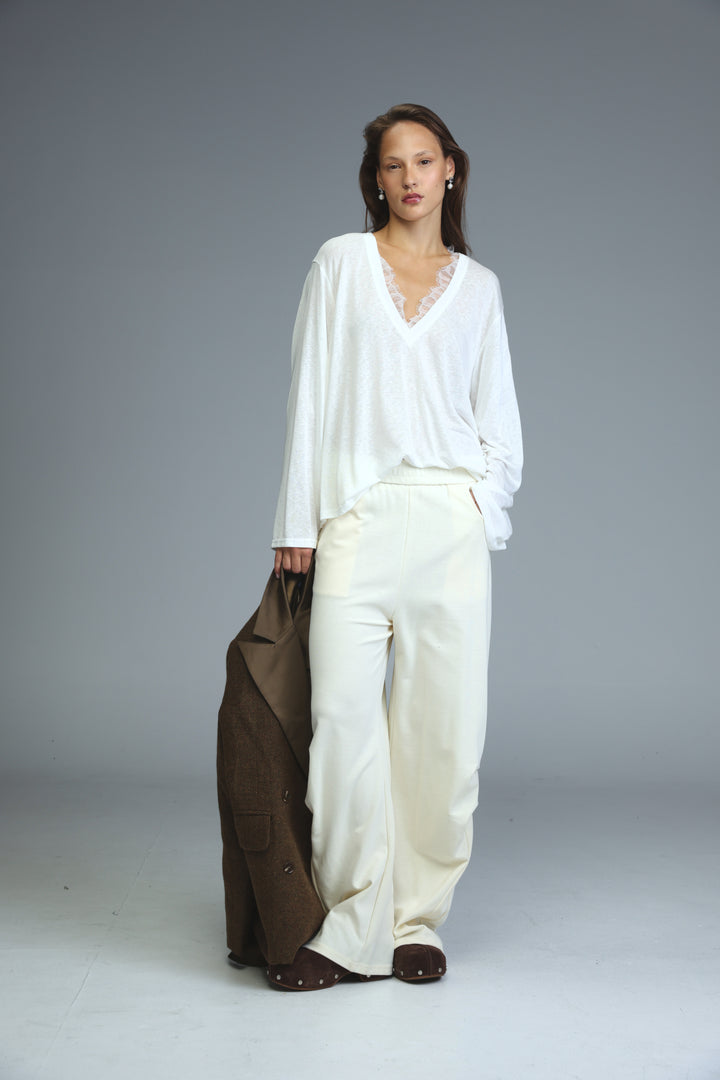 Cream joggers paired with a flowing white blouse featuring delicate lace trim at the v-neckline front view