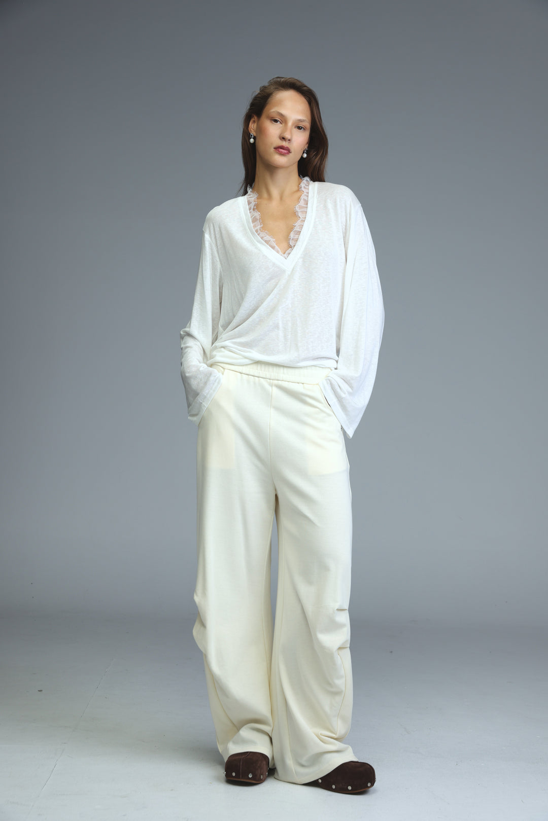 Cream joggers paired with a white blouse featuring delicate lace trim at the neckline shown from the front