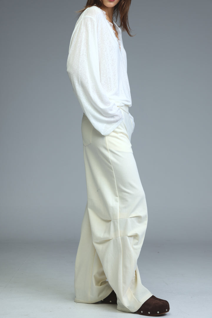 A flowing white blouse with long loose sleeves and relaxed fit paired with cream joggers shown from the front