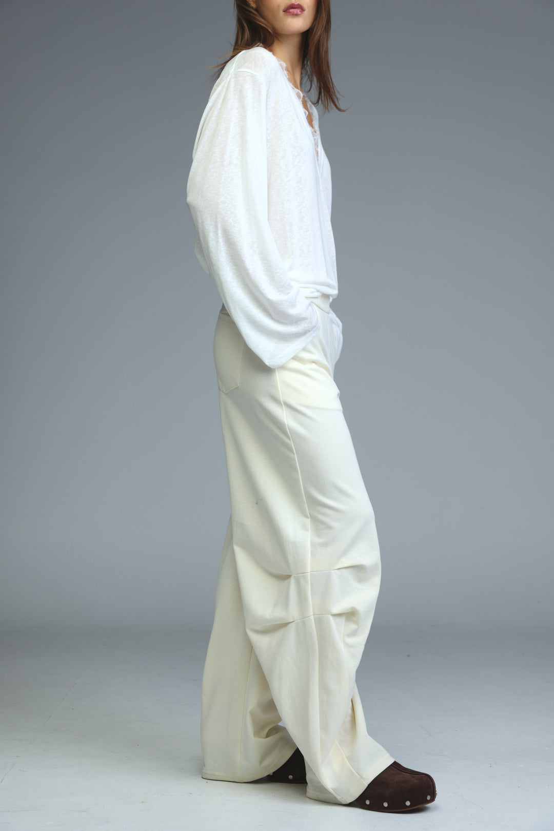 A woman wearing 646 cream joggers with wide-leg fit paired with a white blouse and brown clog-style shoes