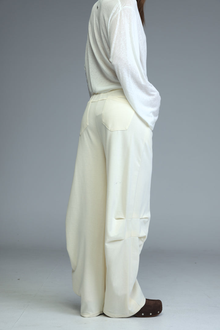 Cream joggers with wide-leg cut, relaxed flowing silhouette, and subtle front pockets shown from the front