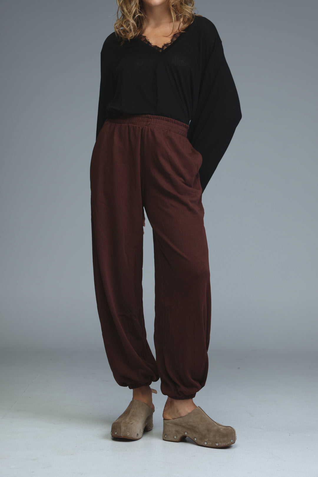 Brown loose-fitting harem pants with elastic waistband and cuffed ankles shown from the front