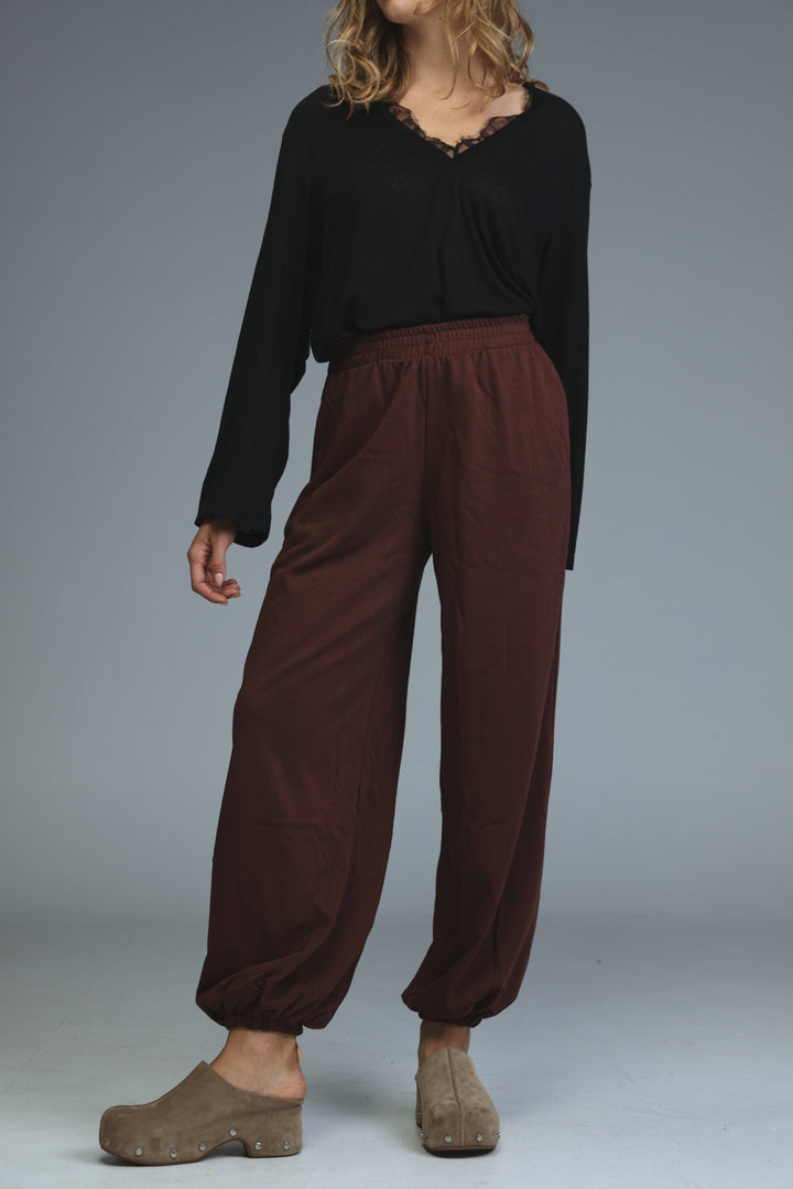Brown loose-fitting joggers with elastic waist and cuffed hems shown from the front