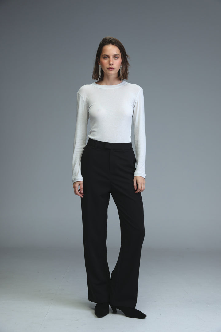 Mid rise tailored black bottoms paired with a minimalist white long-sleeved top with round neckline and shoulder seams front view
