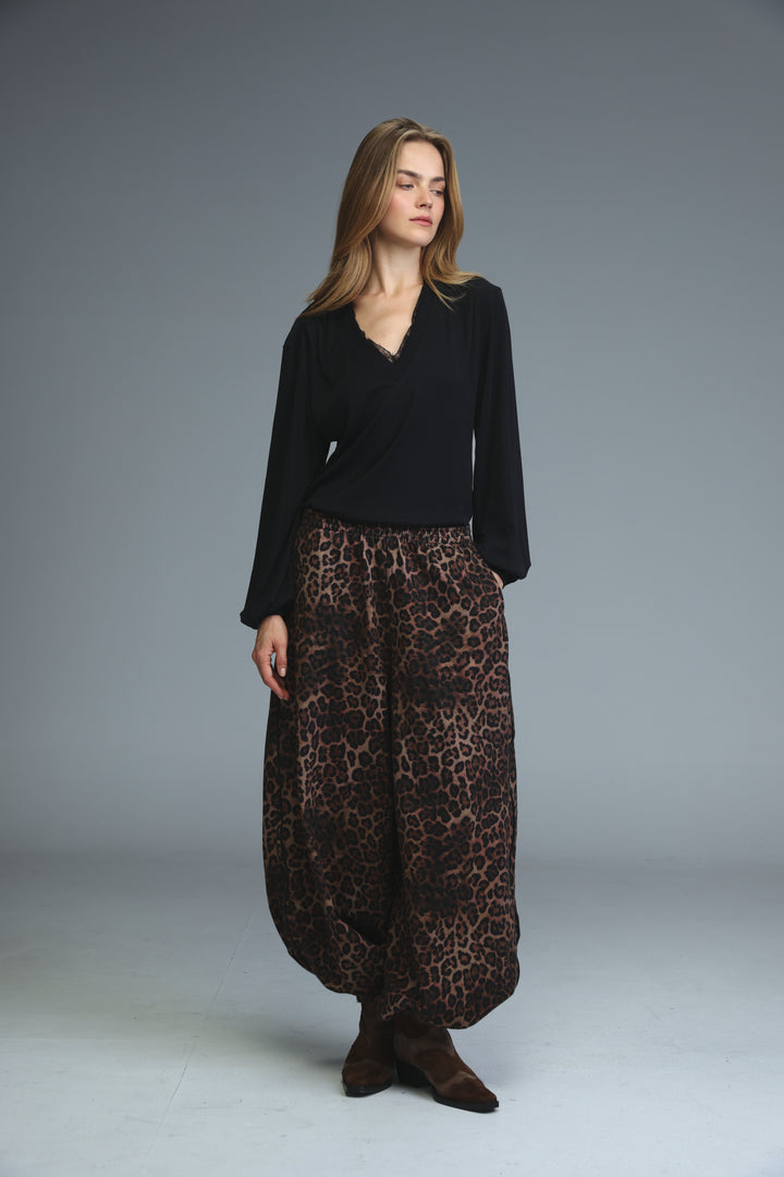 Marry black shirt paired with flowing wide-leg leopard-print pants in rich brown and black tones front view