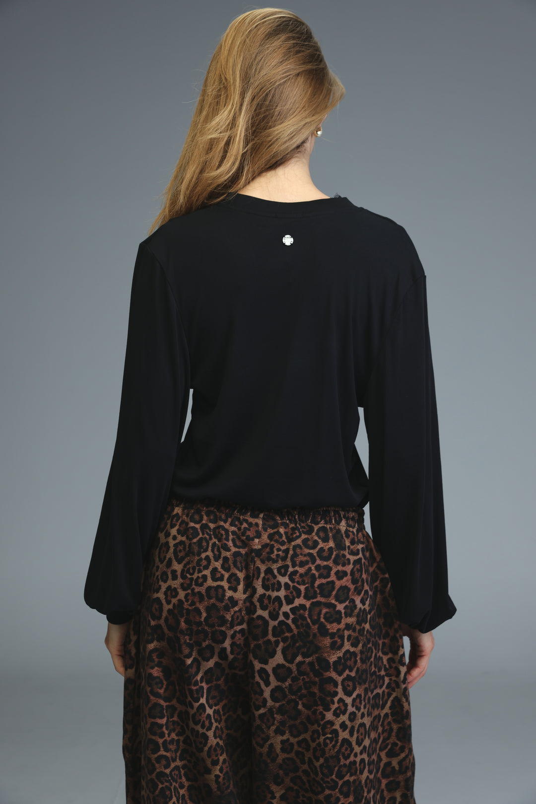 Black long-sleeved marry shirt with a subtle silver emblem at the neckline shown from the front