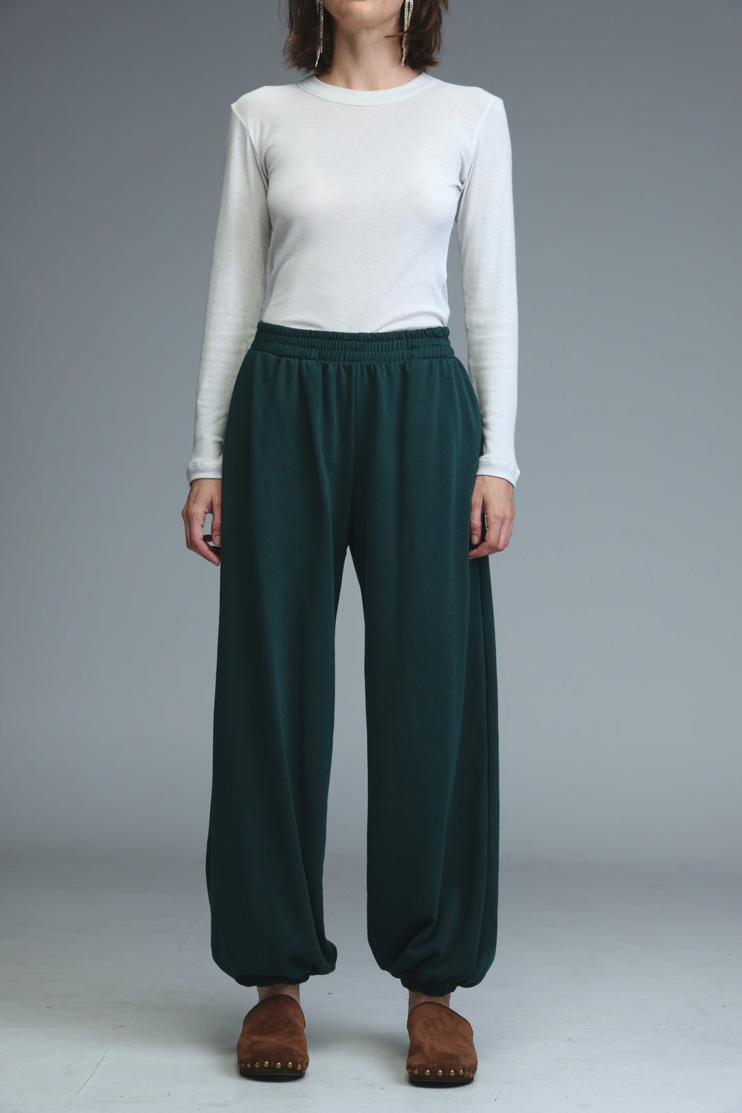 Dark green try green joggers with loose fit and elastic waist shown from the front with flowing fabric