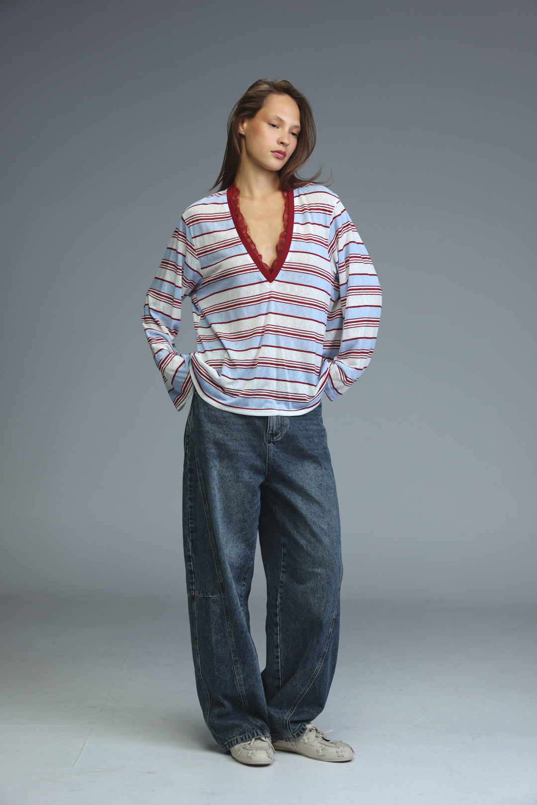 A woman wearing a glow red striped long-sleeved shirt with horizontal stripes and a deep red lace-trimmed v-neckline
