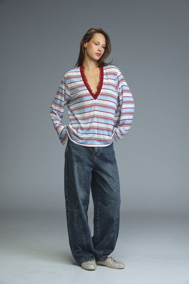A woman wearing a glow red striped long-sleeved shirt with horizontal stripes and a deep red lace-trimmed v-neckline