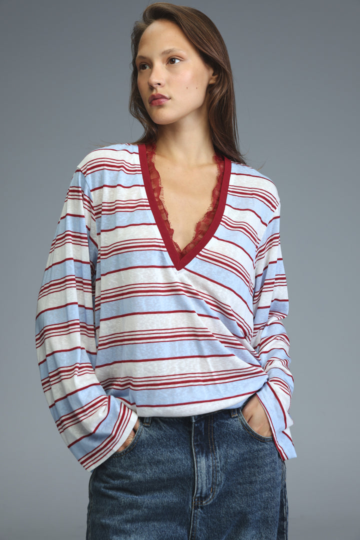 A woman wearing a glow red striped long-sleeved shirt with light blue white and red horizontal stripes and a red lace v-neckline