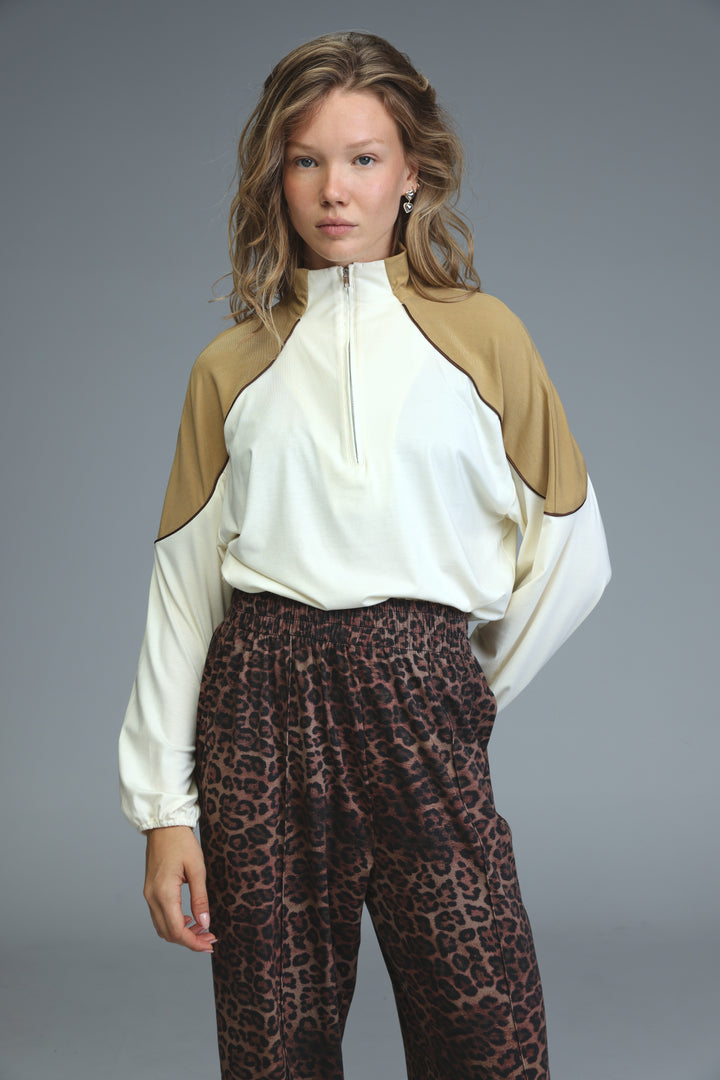 A woman wearing an allure cream sweatshirt with a two-tone cream and tan zip-up front panel