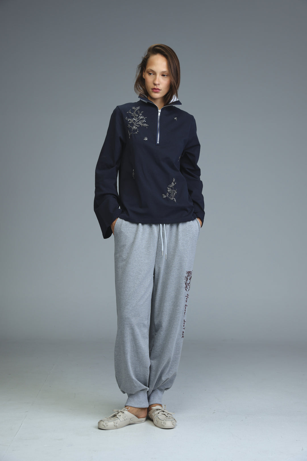 Navy blue half-zip hoodie with white embroidered floral patterns on the chest and sleeves shown from the front