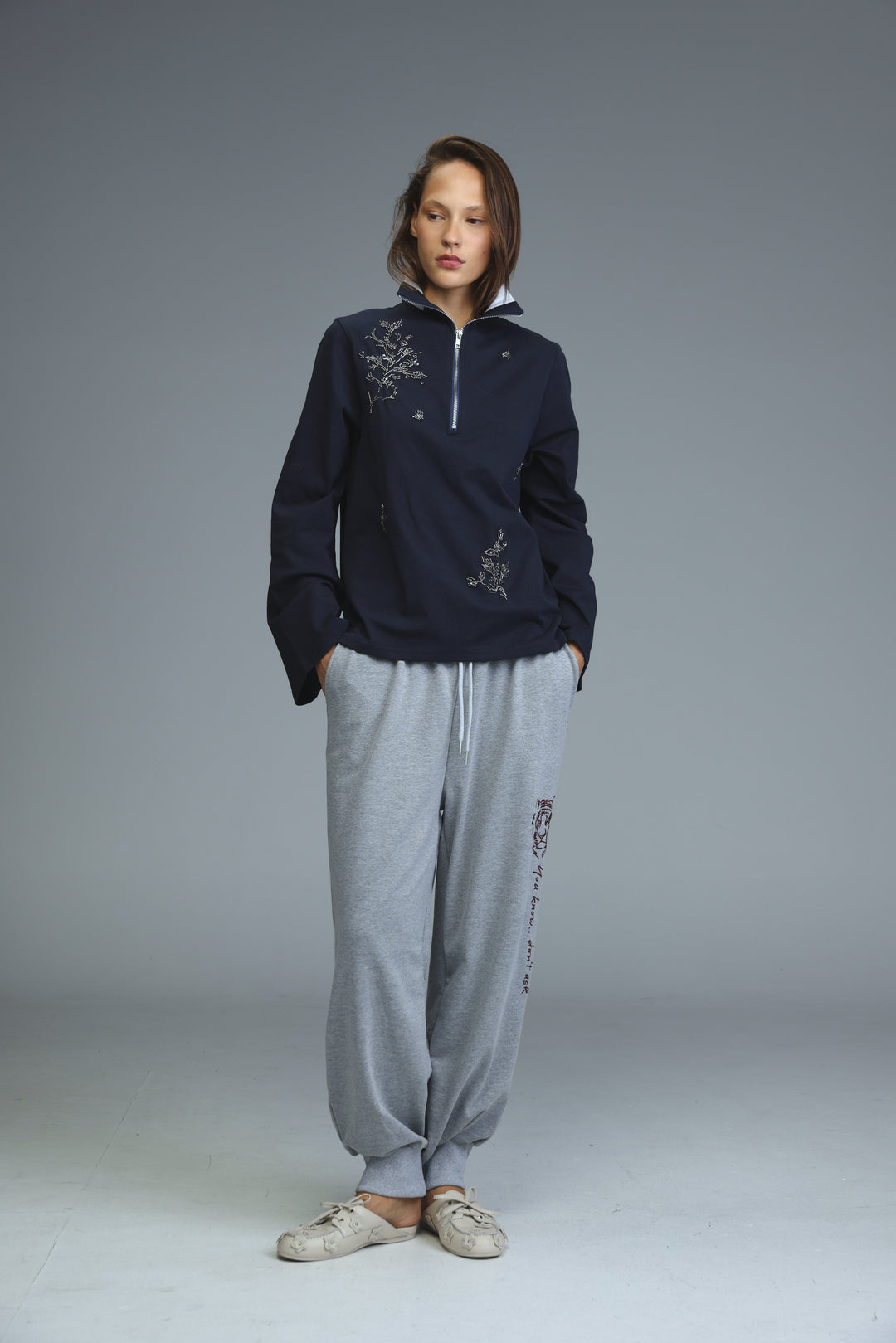 Navy blue half-zip sweatshirt with white embroidered floral patterns on the chest and sleeves shown from the front