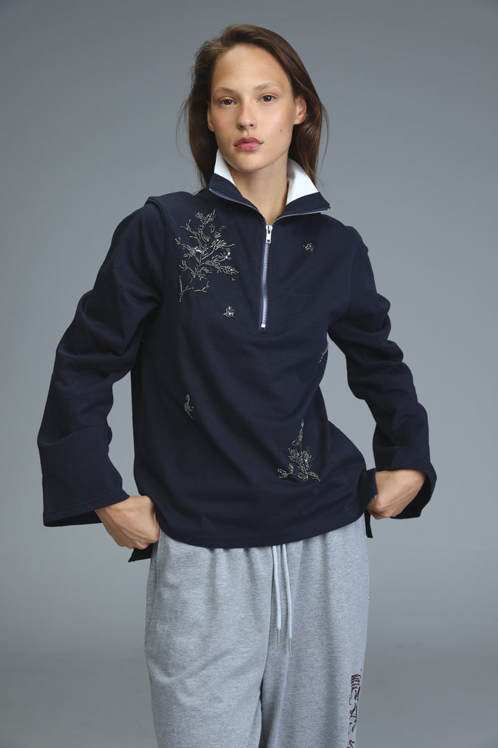 Navy polo zip-up hoodie with silver embroidery of branches and small floral motifs on the front