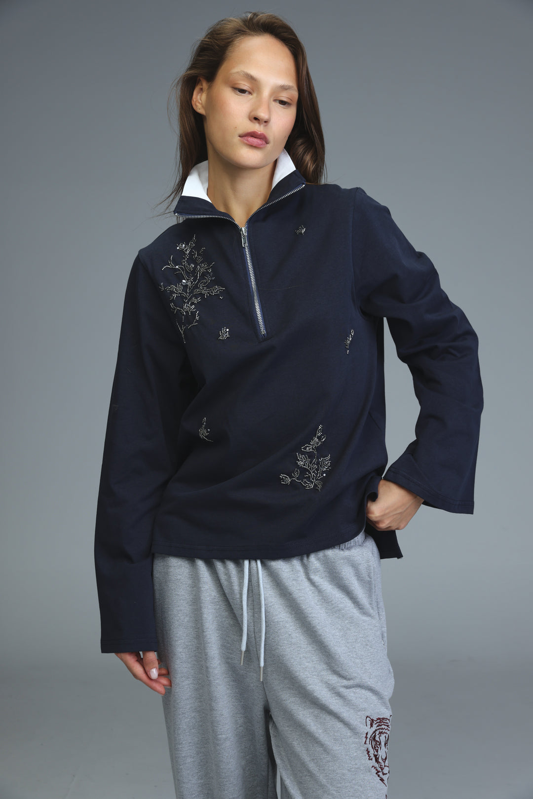 Navy blue half-zip sweatshirt with silver floral embroidery and white inner collar showing the front view