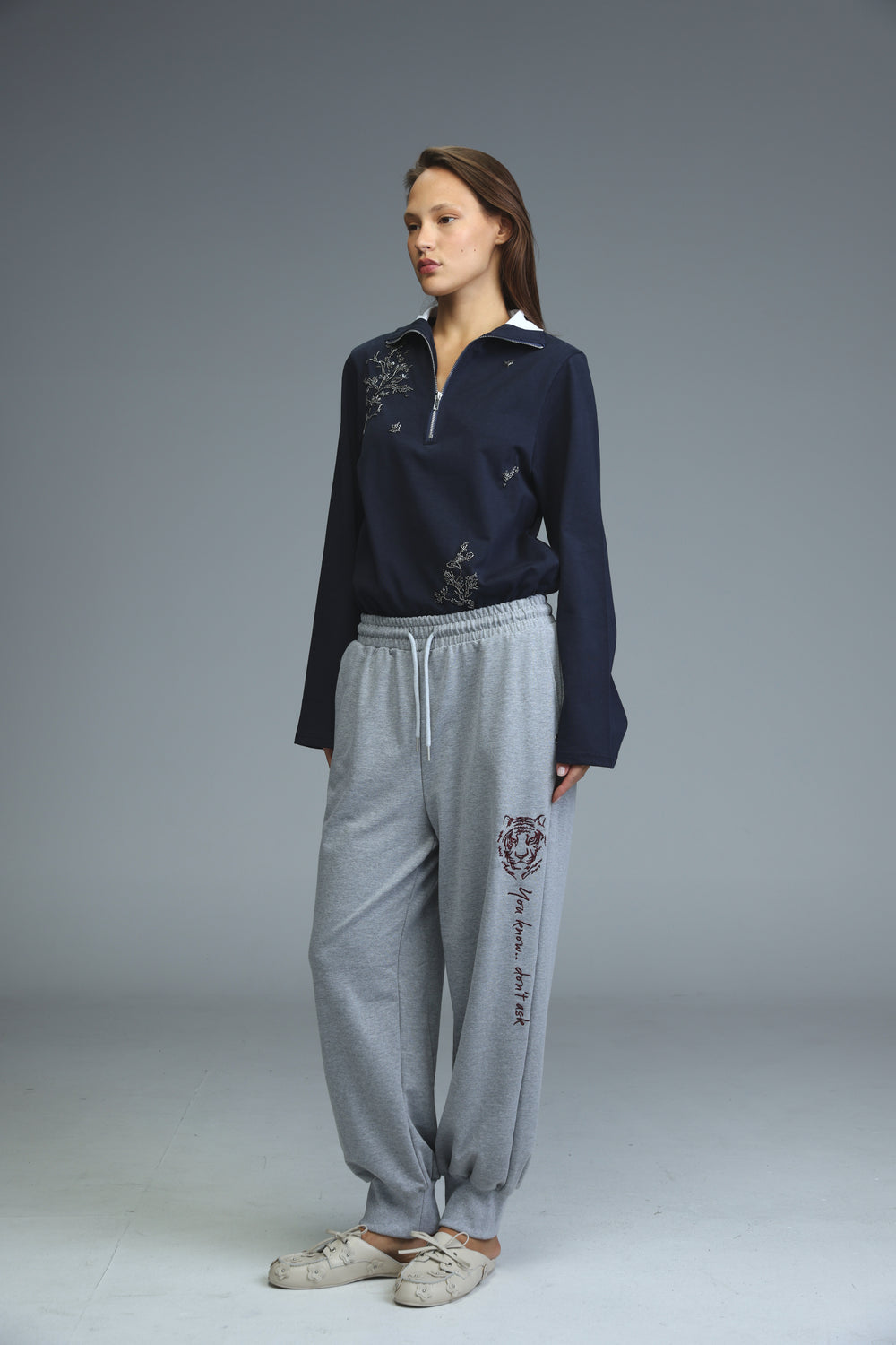 Iconic grey joggers with tiger graphic and text along the side seam shown from the side view