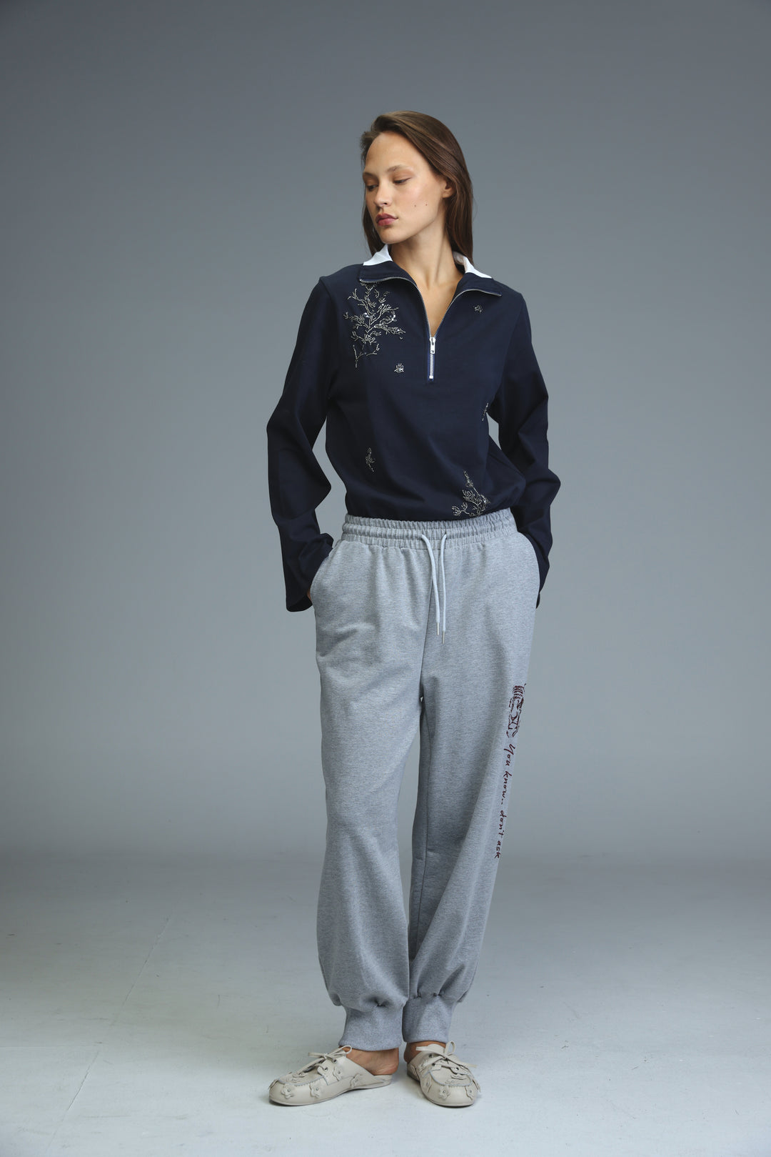 Navy blue zip-front sweatshirt with white collar and silver embroidery on the chest shown from the front