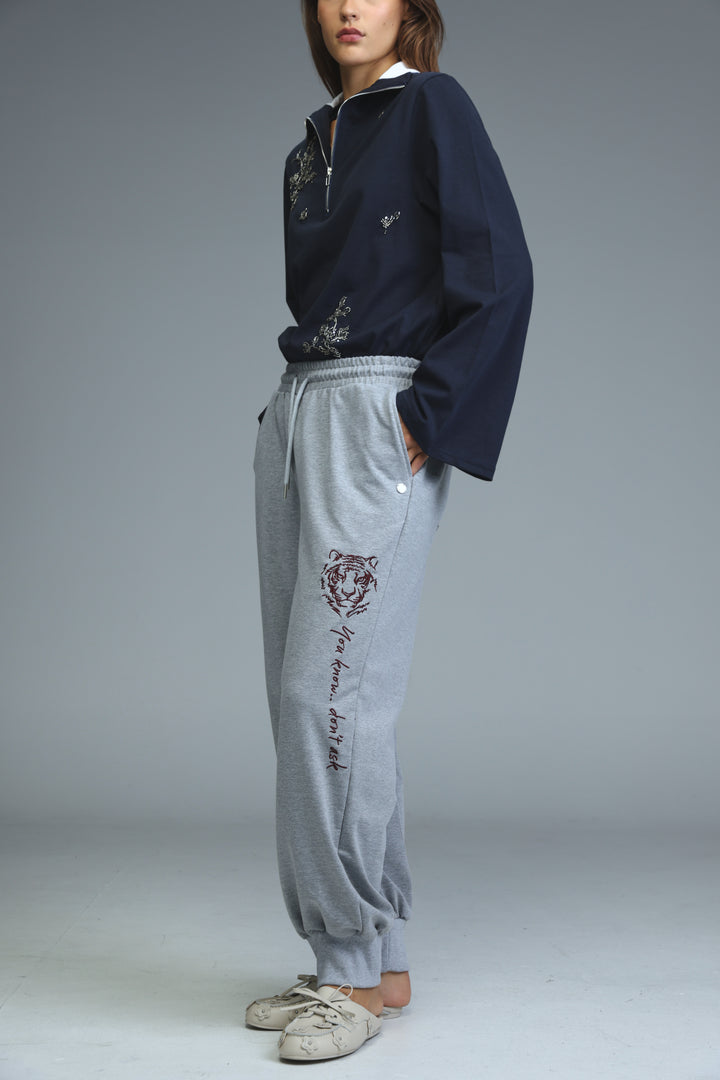 Light gray joggers with tiger embroidery and script text on the leg shown from the side view