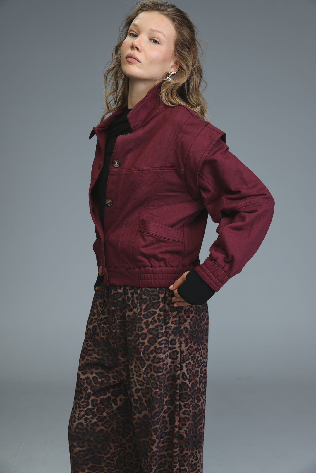 Puzzle wine jacket showing a maroon bomber style with black ribbed cuffs and a high collar from the front view
