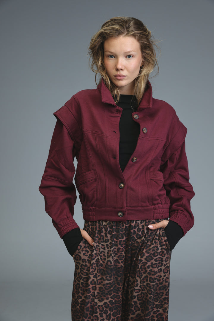 Maroon denim jacket with collar, front button closure, and two side pockets shown from the front called puzzle wine jacket