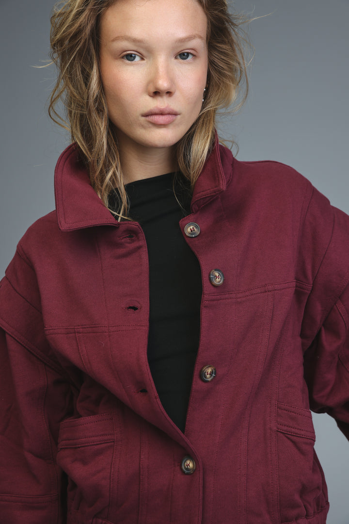 Maroon puzzle wine jacket with structured collar, button closures, and visible stitching details shown from the front