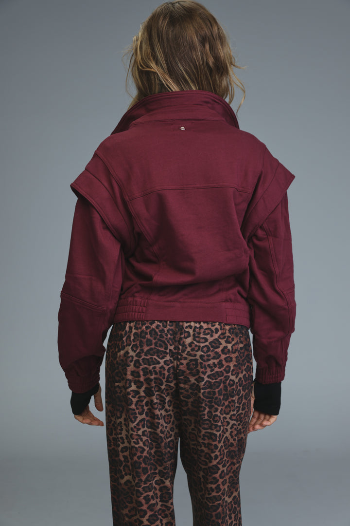 Maroon puzzle wine jacket with a high collar and ruffled sleeves shown from the front