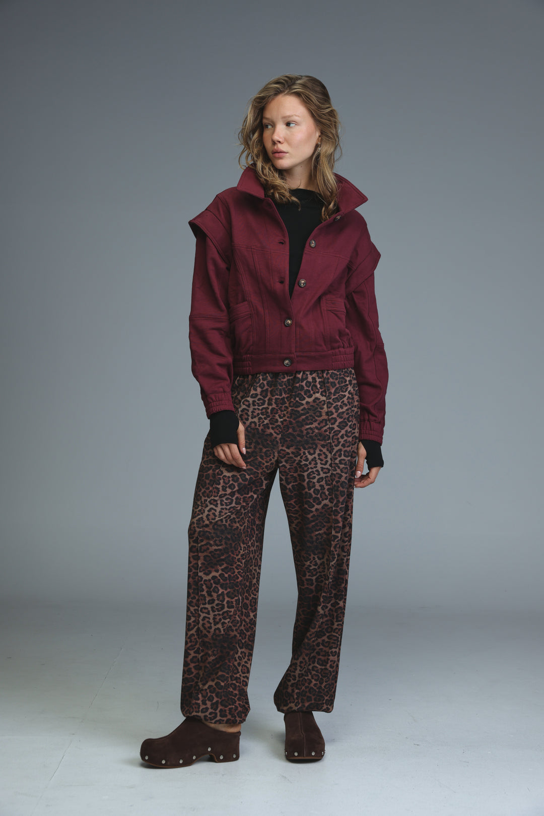 Maroon cropped puzzle wine jacket with high collar and button closures shown from the front