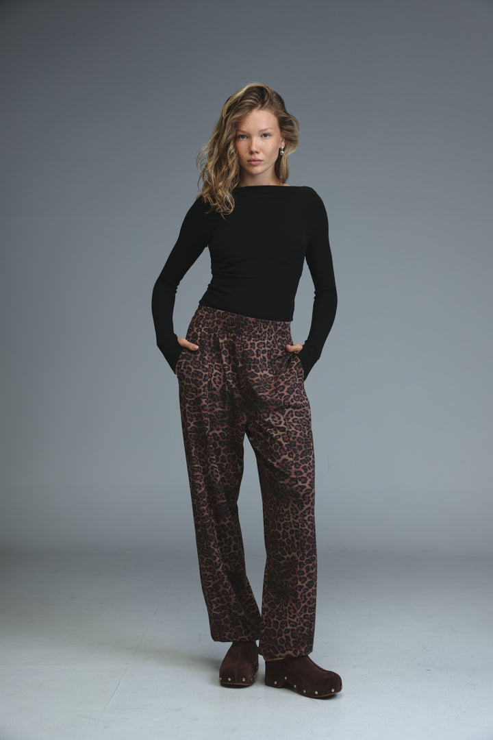 Black boat neck bodysuit paired with brown leopard print wide leg trousers with elastic waistband viewed from front