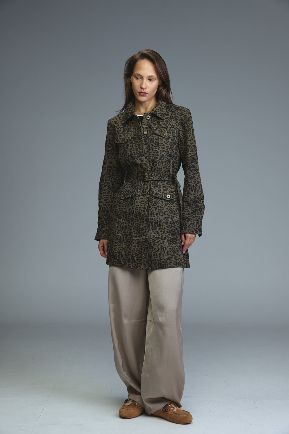 A woman wearing a dark olive and brown leopard-print belted jacket with two front pockets in front view