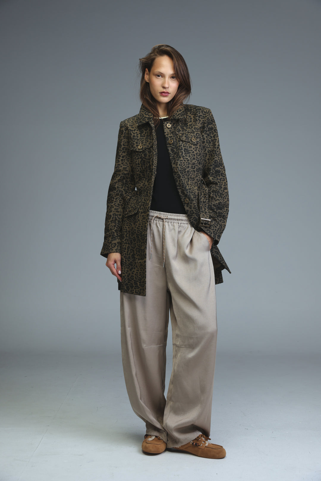 A front view of a woman wearing a dark green and brown opulence leopard jacket with two front pockets