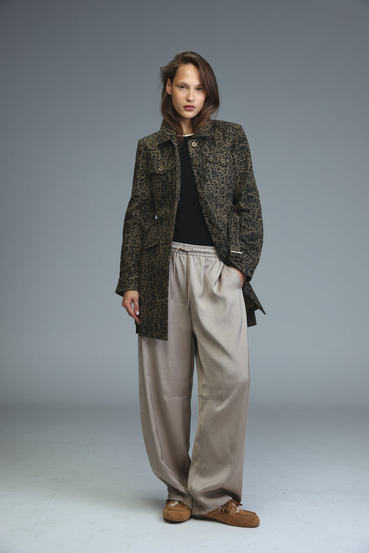 A front view of a woman wearing a dark green and brown opulence leopard jacket with two front pockets