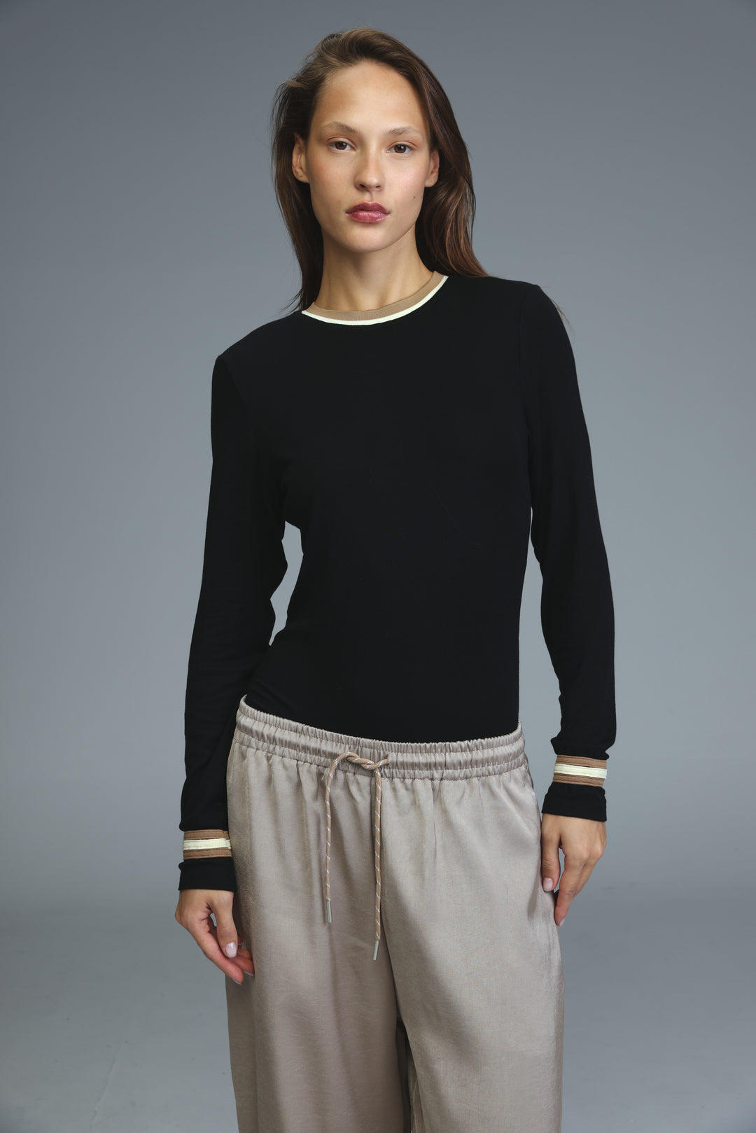 Black long-sleeved bodysuit with cream-colored ribbed trim at neckline and cuffs shown from the front