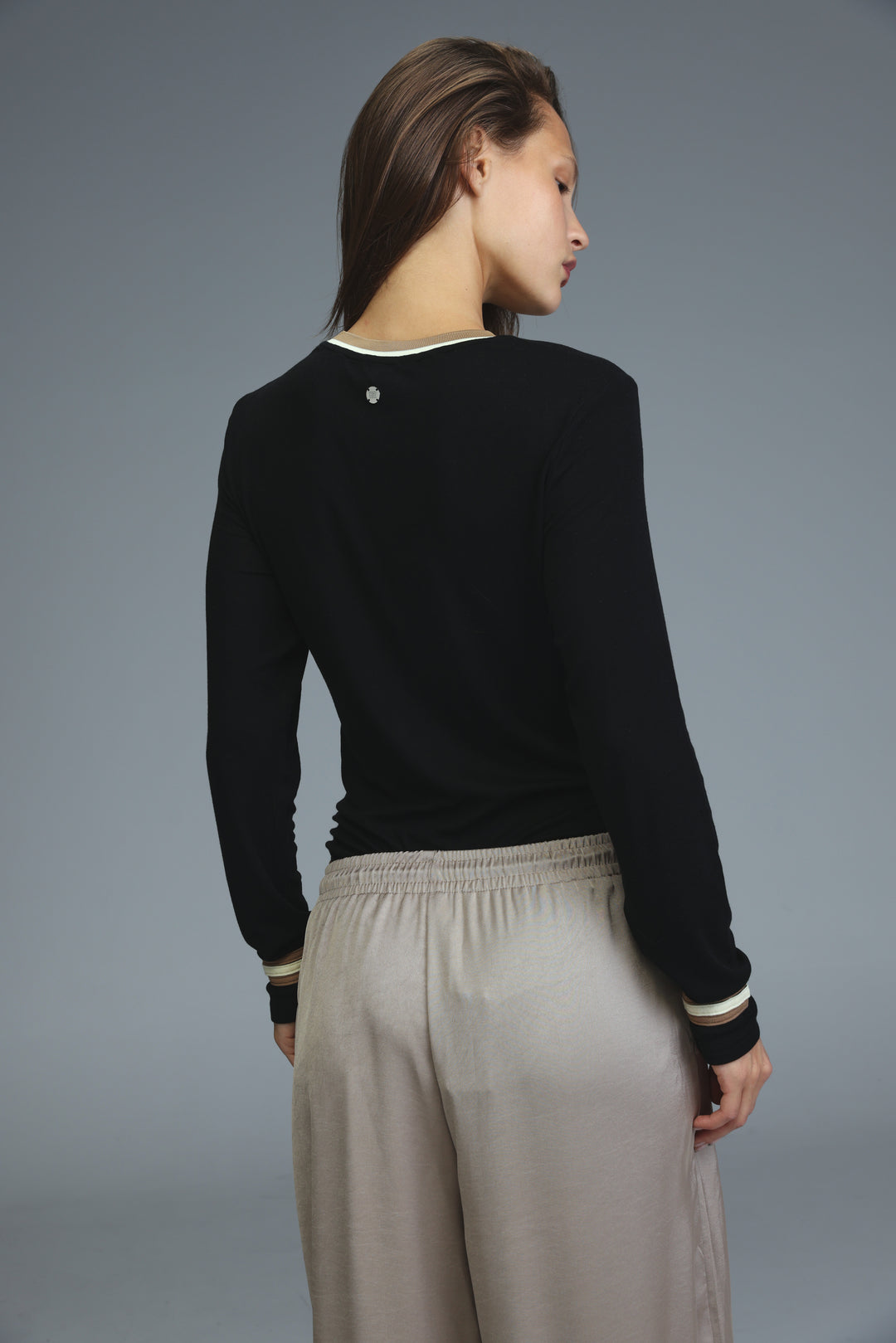 Black long-sleeved bodysuit with cream ribbed trim at neckline and cuffs shown from the front