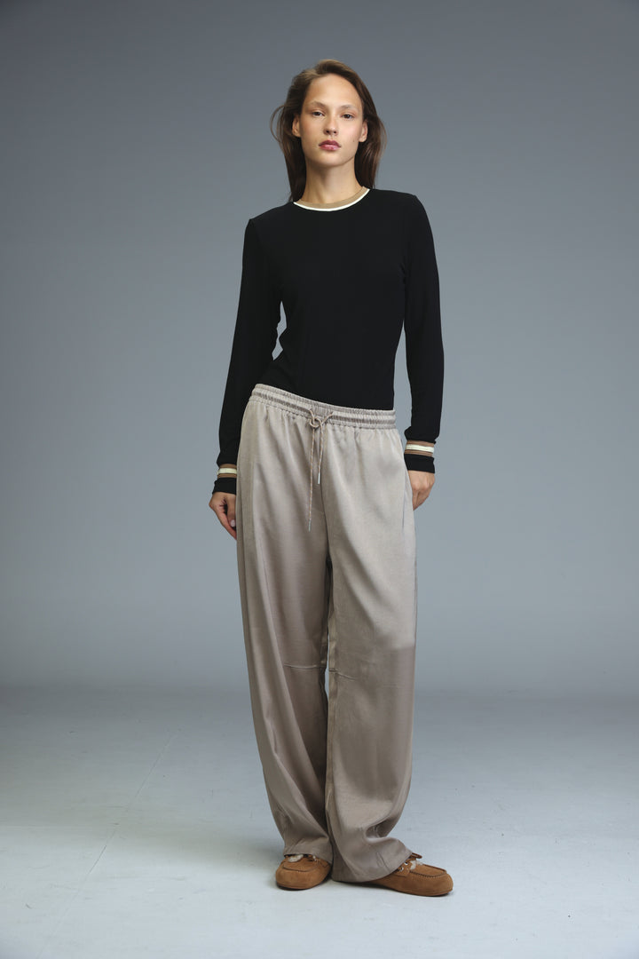 Golden camel bottoms paired with a black long-sleeved knit top featuring a white ribbed crew neckline and striped cuffs