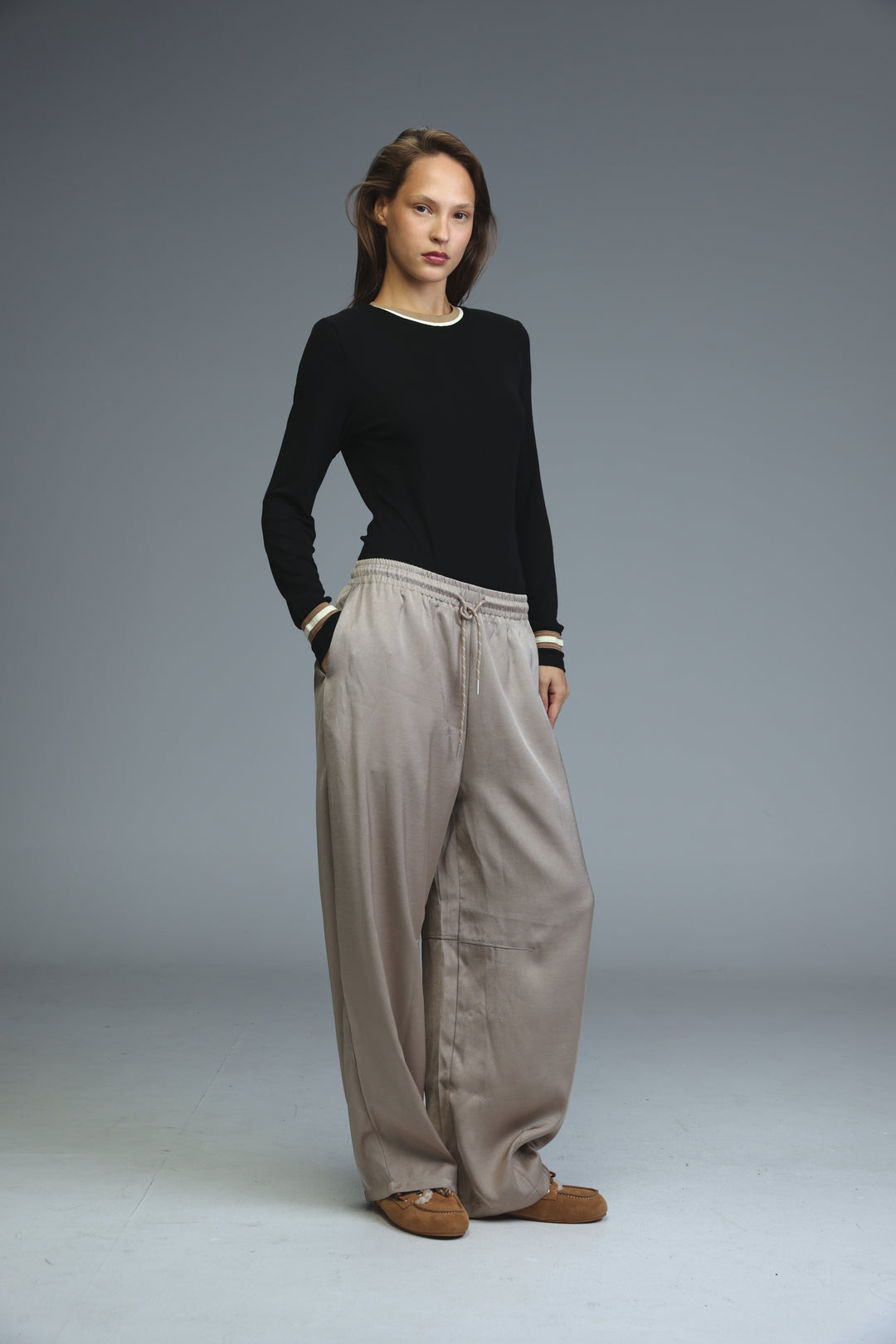 Golden camel loose-fitting wide-leg pants with elastic waistband and subtle striped cuffs shown from front view