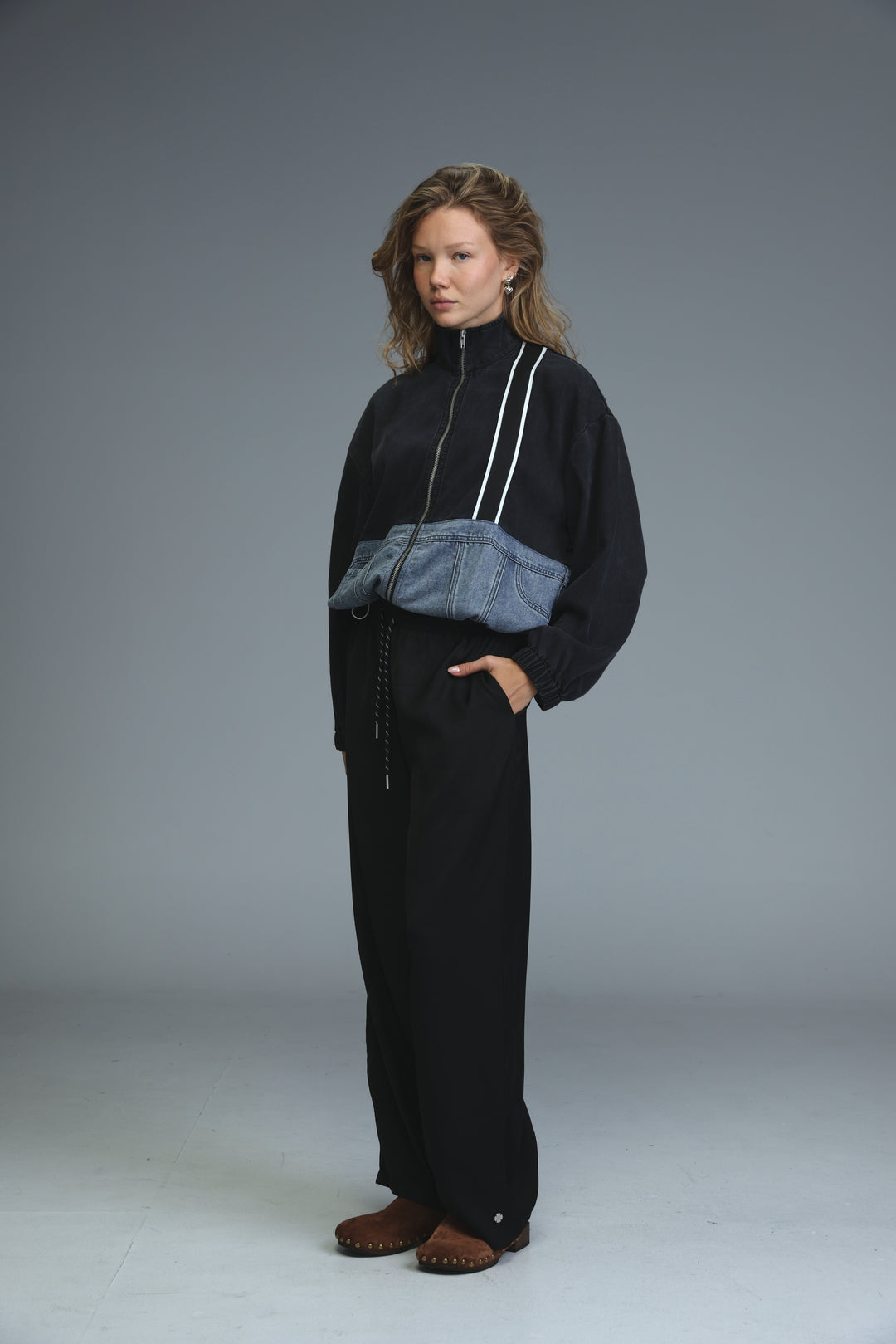 Black soft denim panel jacket with white zipper trims and denim patch at the waist shown from the front