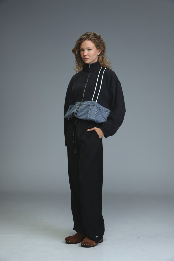 Black soft denim panel jacket with white zipper trims and denim patch at the waist shown from the front
