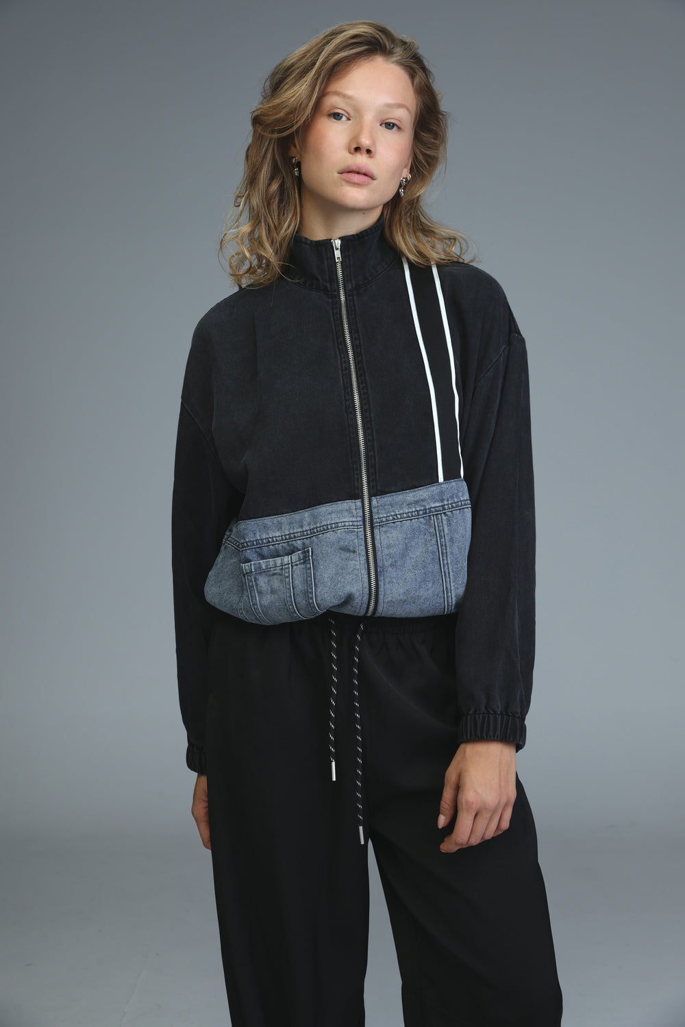 Black and blue denim patchwork zip-up soft denim panel jacket with white zipper trim shown from the front