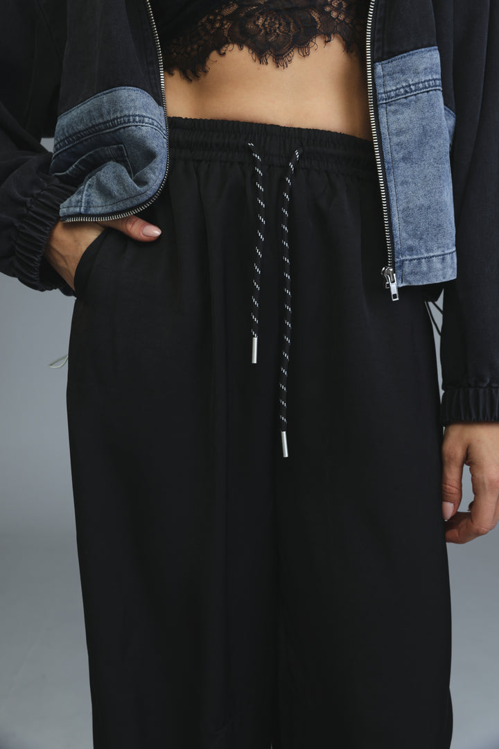 Golden black bottoms featuring relaxed fit black drawstring pants with subtle texture shown from front view