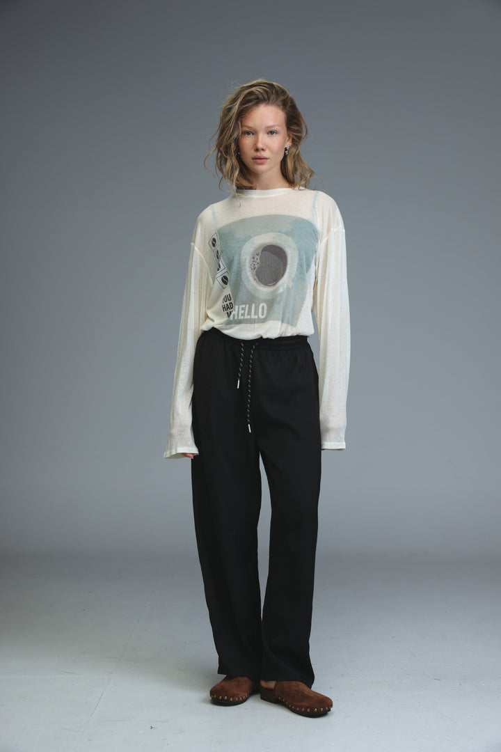 White long-sleeved graphic tee with circular black hello design paired with golden black bottoms shown from front