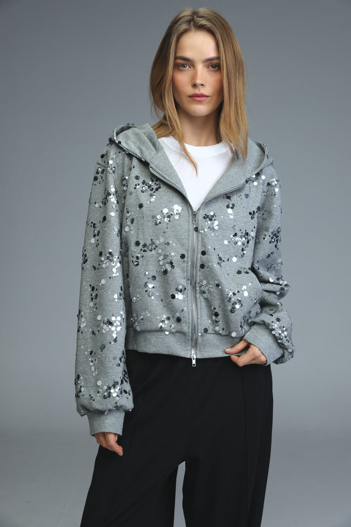 Gray sequined zip-up hoodie with subtle shimmer and black circular embellishments shown from front
